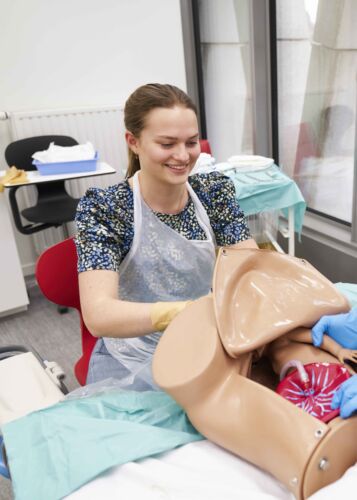 Verpleegkunde en Vroedkunde student die bezig is met een nep bevalling