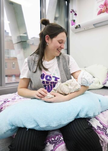 Verpleegkunde en Vroedkunde student die een neppe baby vasthoudt