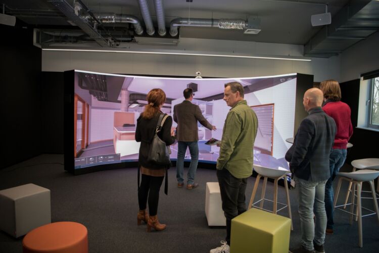 Een groot curved scherm en mensen die VR uitproberen