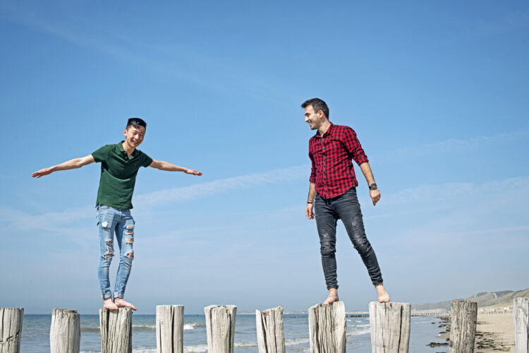 Students balancing on wood beams at the beach