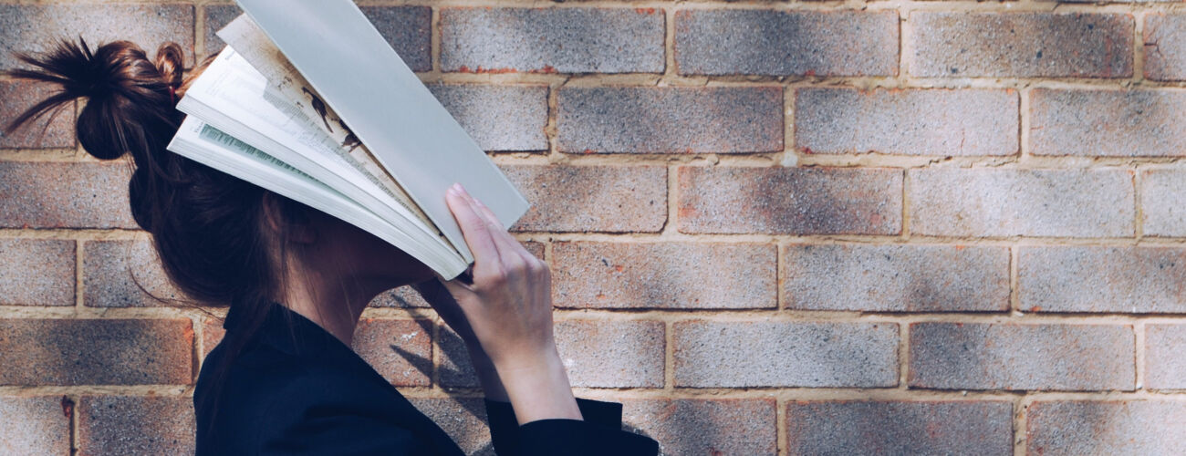 Een gefrustreerd meisje die haar hoofd verbergt met een boek