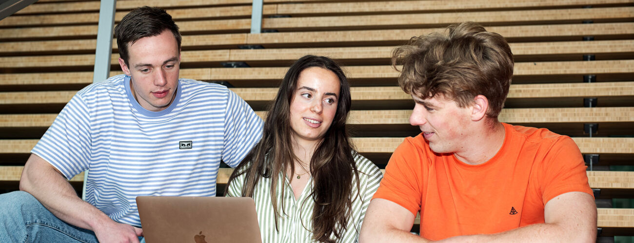 Drie Bedrijfskunde studenten die samen kijken naar een laptop