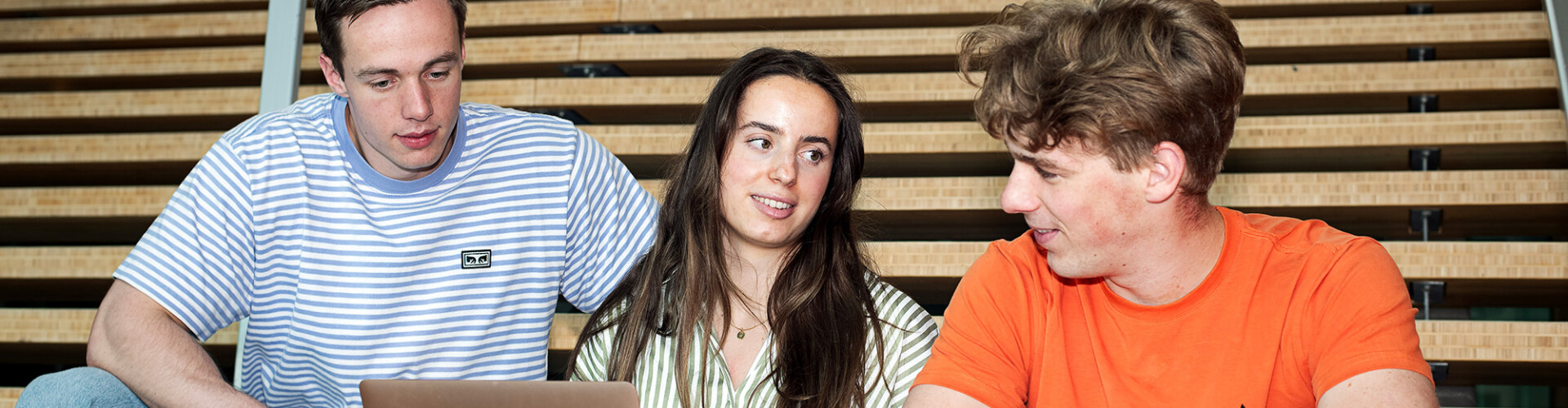 Drie Bedrijfskunde studenten die samen kijken naar een laptop