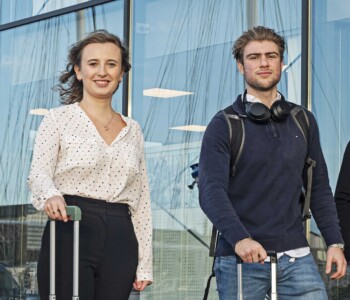 International Business students walk together outside of the airport with suitcases in their hands