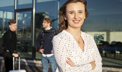 Portret International Business student bij een vliegveld met andere studenten in de achtergrond