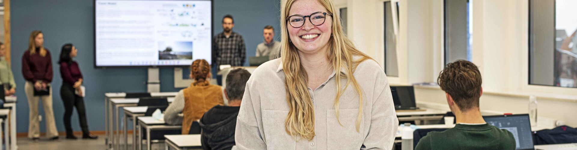 Female student smiling at the camera in a classroom at HZ