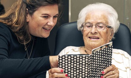 Social Work student die samen met een oudere vrouw in een boekje kijkt