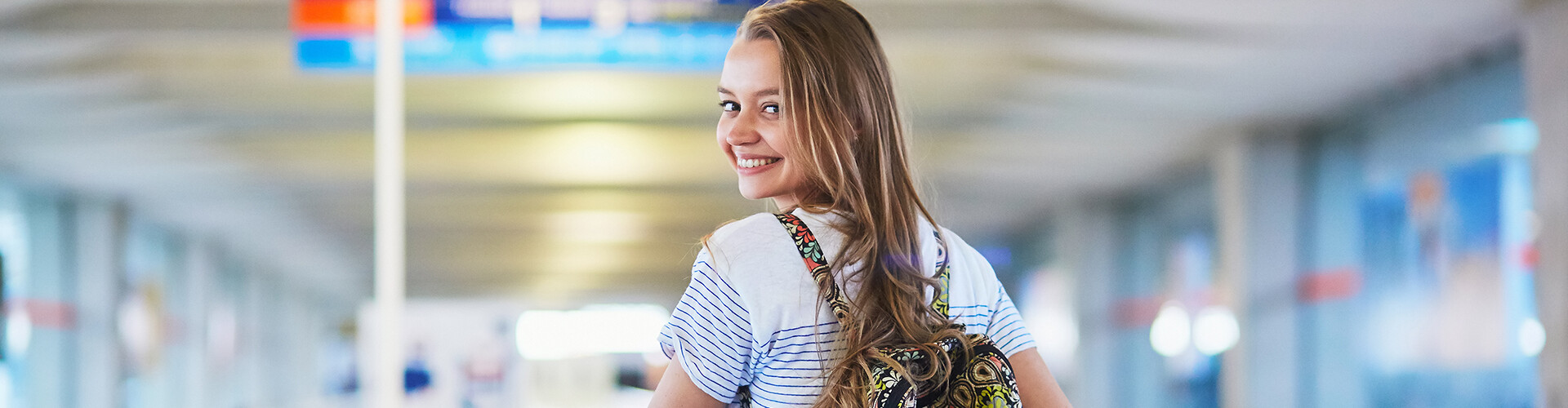 Student in een luchthaven die over haar schouder kijkt