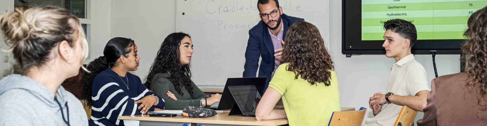 Studenten in een klaslokaal met een docent die uitleg geeft