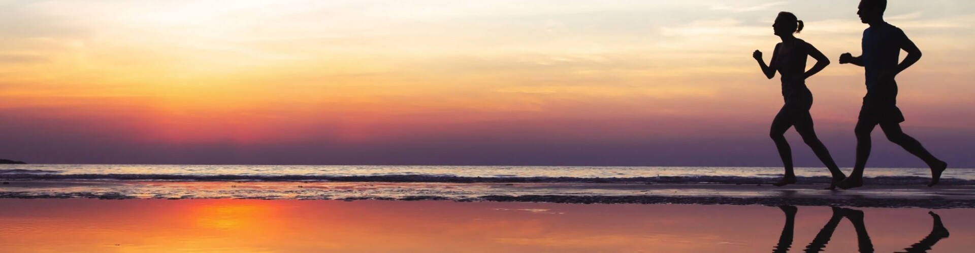 Mensen die hardlopen op het strand tijdens een zonsondergang