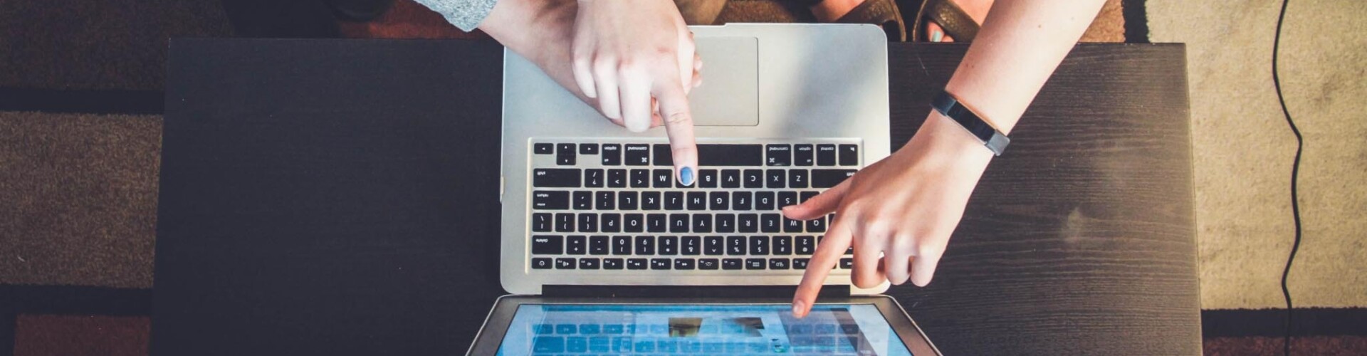 Verschillende handen wijzen naar een laptop