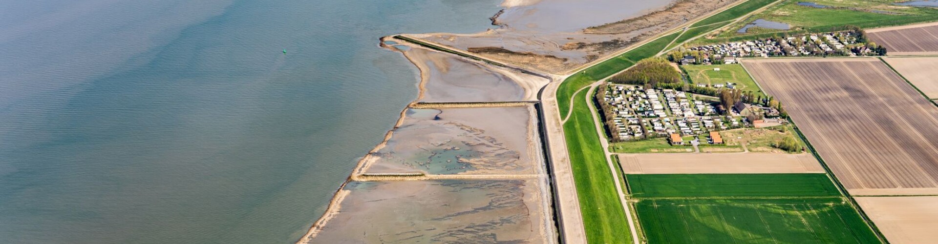 Een rivier met weilanden er naast