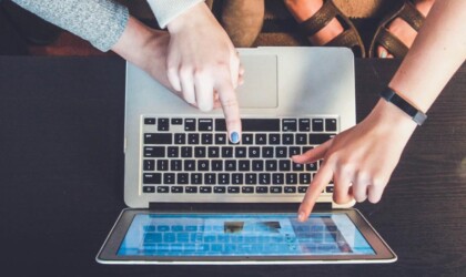 Verschillende handen wijzen naar een laptop