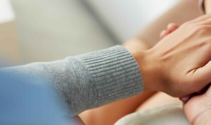 Twee handen die de hand van iemand anders vasthouden