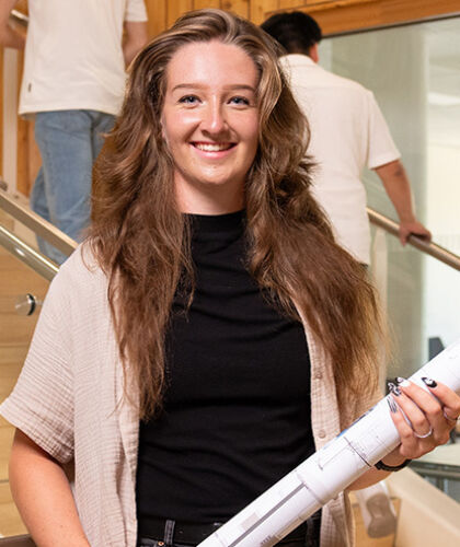 Desiree staat bij een trap in het HZ-gebouw met een bouwtekening in haar handen.