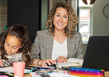 Deeltijd student Tamara maakt haar huiswerk aan de eettafel met knutselende kinderen