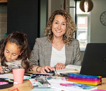 Deeltijd student Tamara maakt haar huiswerk aan de eettafel met knutselende kinderen