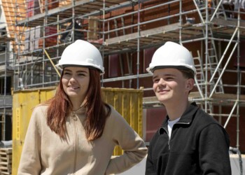 Twee bouwkunde studenten op een bouwplaats met helmen op