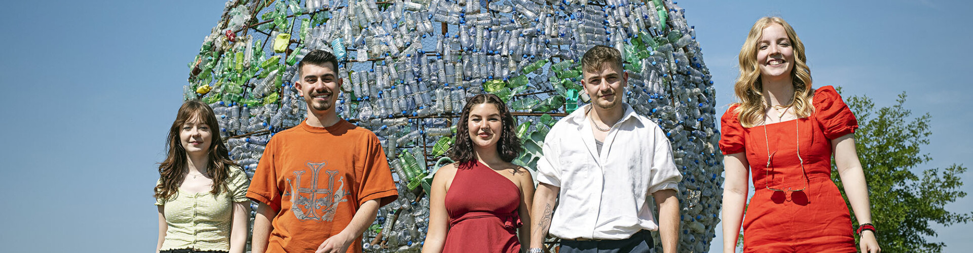 Groep Global Project and Change Management studenten voor een grote wereldbol gemaakt van plastic flesjes