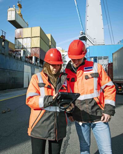 Twee Logistics Engineering studenten staan in een haven naast een container schip