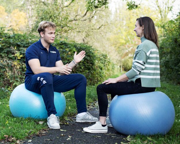 Sportkunde student samen met een vrouw op een ergonomische zitbal