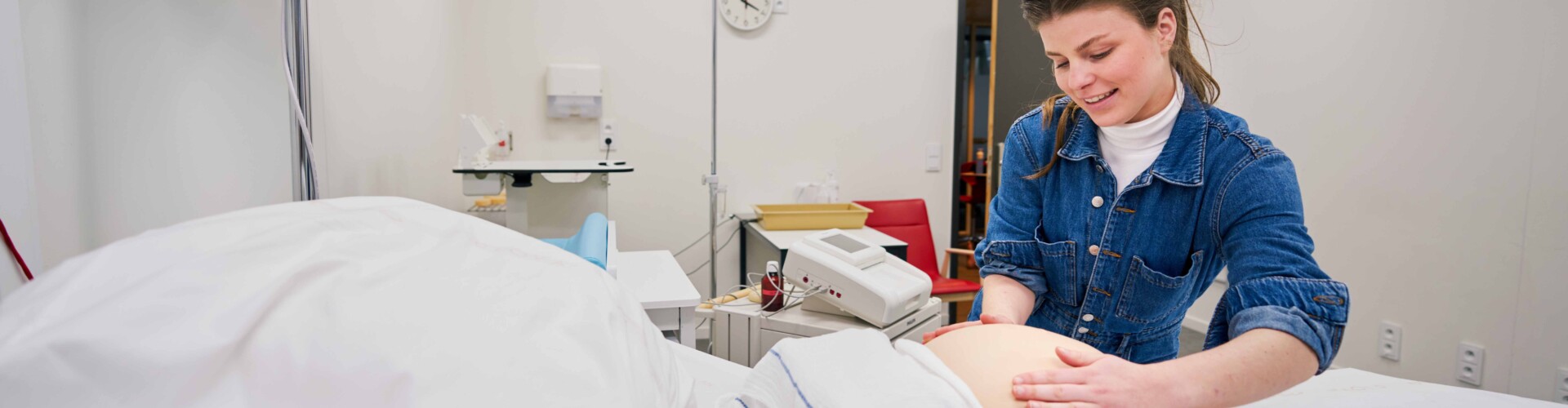 Verpleegkunde en Vroedkunde student oefent op een pop van een zwangere vrouw
