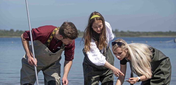 Drie watermanagement studenten die onderzoek doen in het water