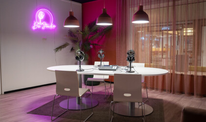 Tafel met podcast apparatuur en op de muur een neon bord met 'De Studio'