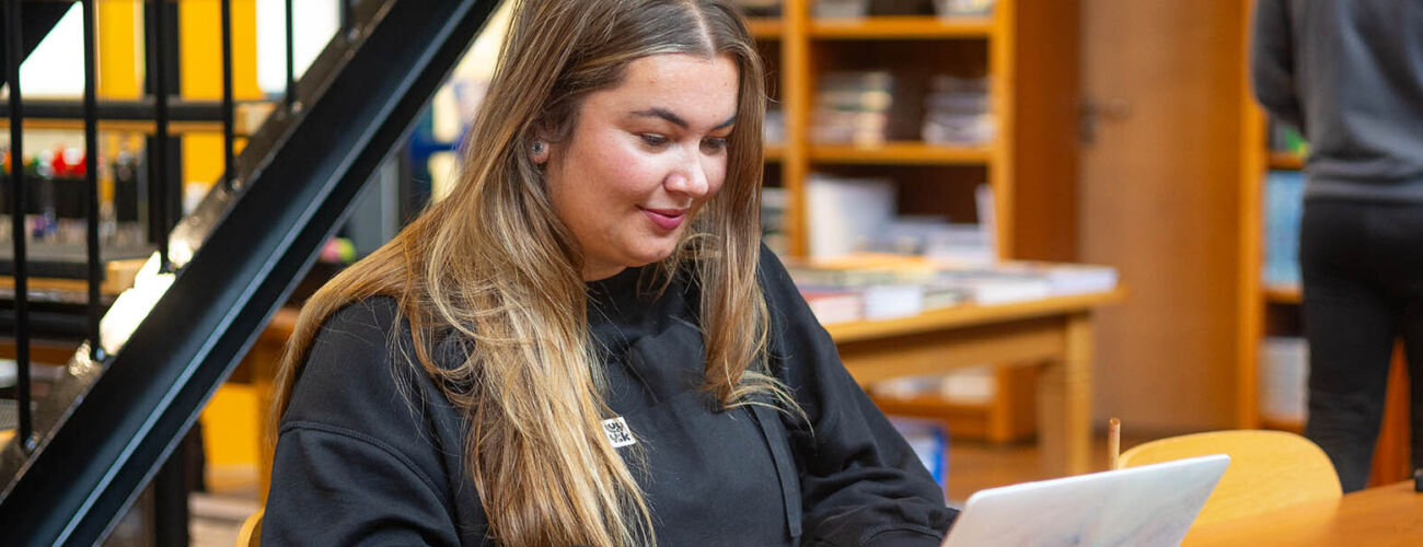 Student achter haar laptop in de HZ Shop