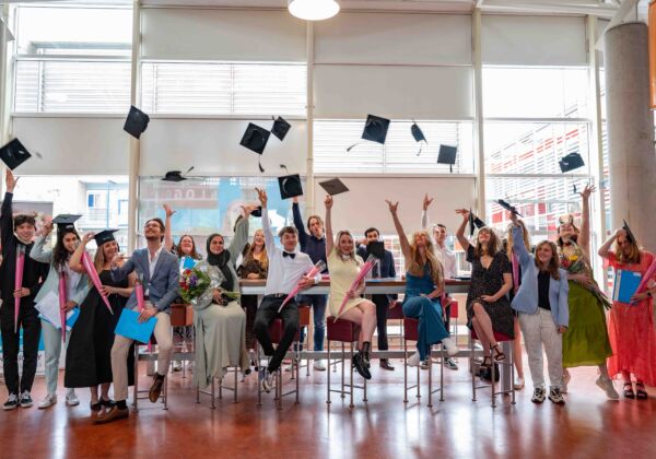 Groep studenten die na de diplomeringen hun hoedje in de lucht gooien