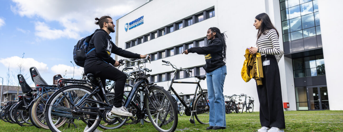 One international male student on his and two international students standing in front of HZ in Middelburg