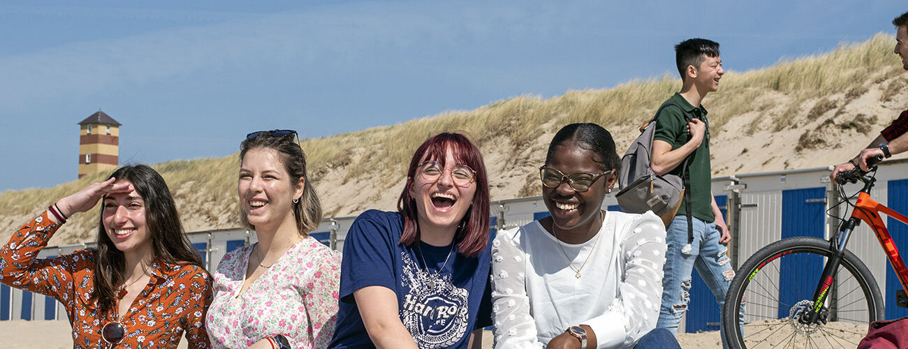 A group of multicultural international students laughing after a lector at HZ University of Applied Sciences on the beach in Vlissingen, Zeeland, The Netherlands,