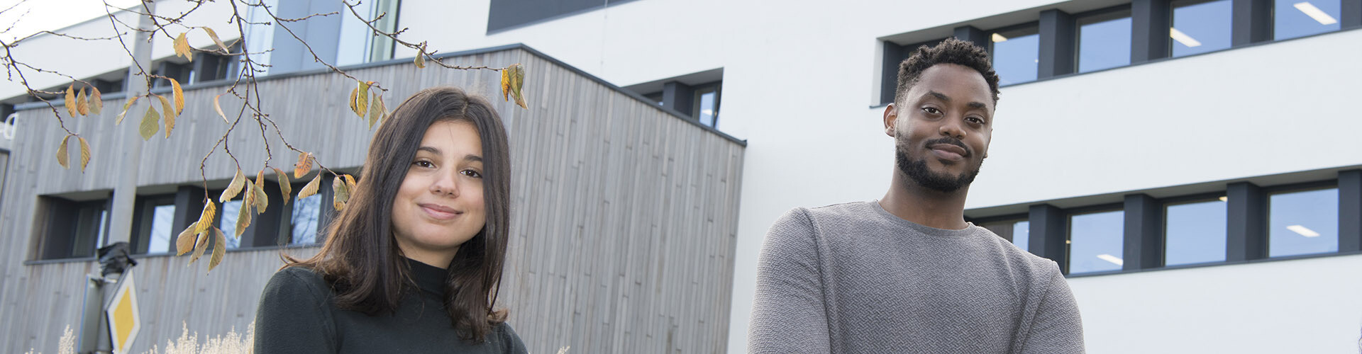 A female and male international student, who study abroad at HZ University of Applied Sciences in the Netherlands, standing before the university building in Middelburg, Zeeland.