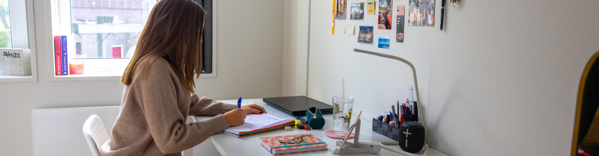 female student sitting on the desk of her dorm