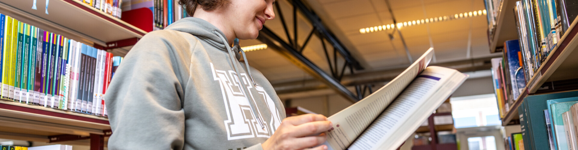 A female international student reading a book at the library in HZ Vlissingen