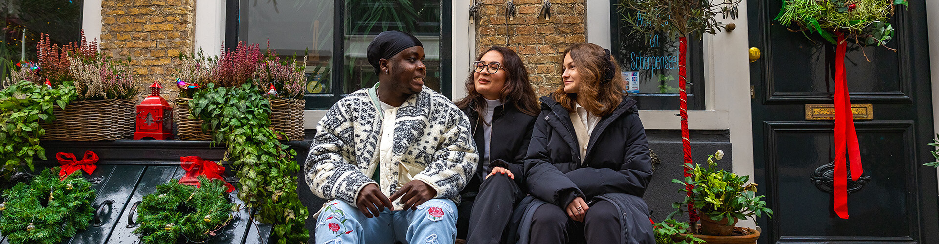 Three international students sitting on a bench in the winter in the cosy old town of Middelburg, the Netherlands