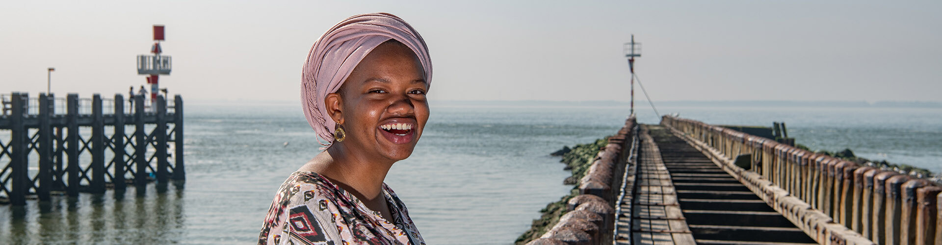 International student smiling with perfect white teeth at the peer in Vlissingen, the Netherlands.