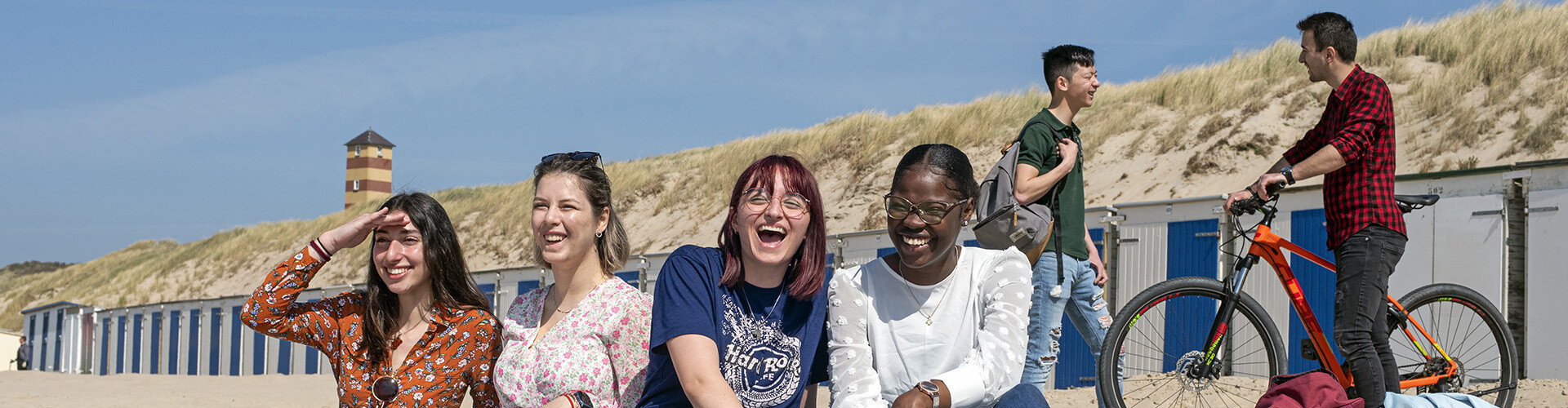 A group of multicultural international students laughing after a lector at HZ University of Applied Sciences on the beach in Vlissingen, Zeeland, The Netherlands,