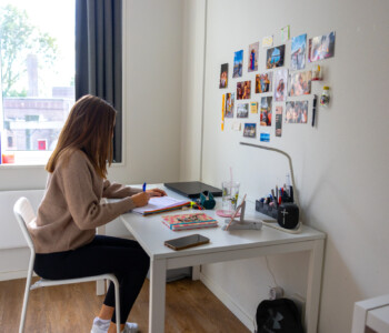 female student sitting on the desk of her dorm