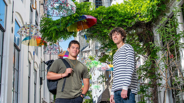 Two male international students standing in the middle of the photogenic street in Middelburg with colourful umbrella's