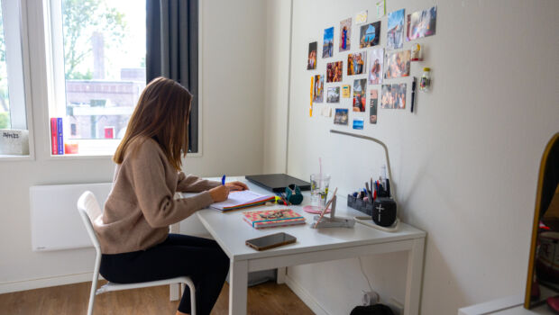 female student sitting on the desk of her dorm