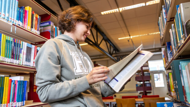 A female international student reading a book at the library in HZ Vlissingen