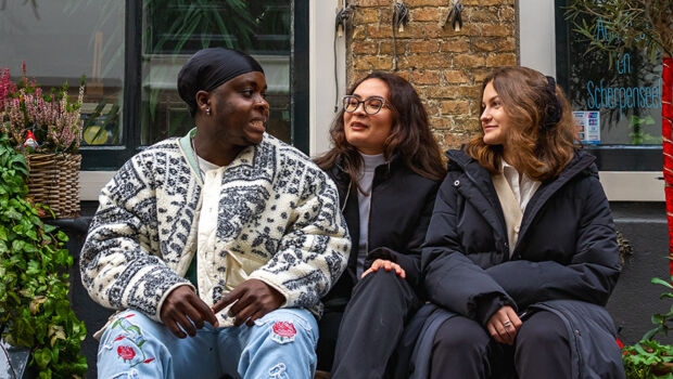 Three international students sitting on a bench in the winter in the cosy old town of Middelburg, the Netherlands