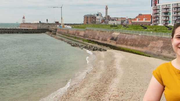 Two female international students are looking over the sea with the skyline of Vlissingen, Zeeland, The Netherlands, in the background/