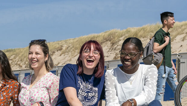 A group of multicultural international students laughing after a lector at HZ University of Applied Sciences on the beach in Vlissingen, Zeeland, The Netherlands,