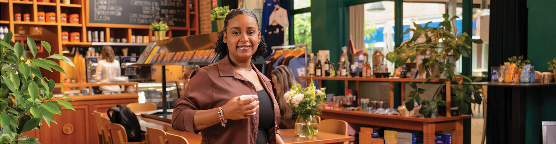 Student grabbing a coffee and smiling at the camera